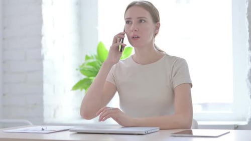 Woman Talking on Smartphone at Desk