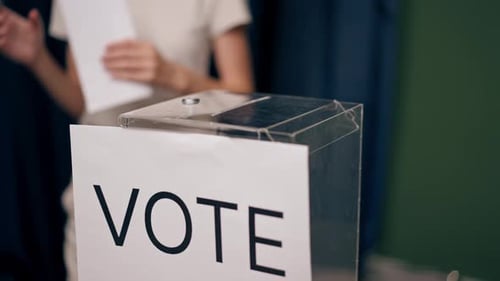 Close Up in the Voting District for the Presidential Election a Young Girl in White Clothes Throws a