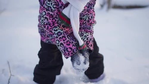 Winterlicher Kindheitsspaß, wenn ein Mädchen den Schnee bergauf wirft, lacht und spielt