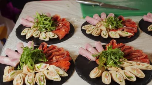 Rollitos de salmón servidos con jamón y pescado rojo sobre tablas de madera en el servicio de catering de la cafetería