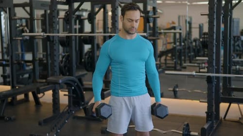 Muskulöser europäischer Mann, der Gewichte hebt und im Fitnessstudio abwechselnd Bizeps-Curls macht. Mittlere Nahaufnahme