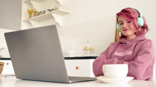 Teenage girl at computer drinking coffee in kitchen