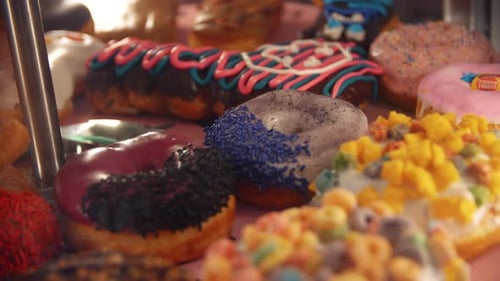 4k close-up slow motion footage of many different unhealthy donuts / with different colorful and swe