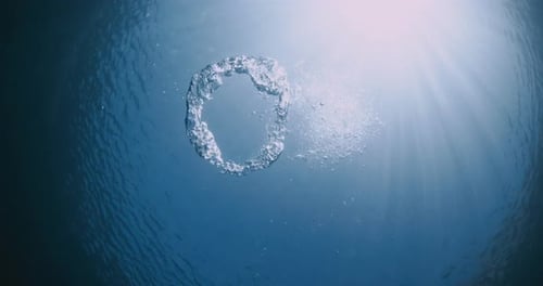 Von Tauchern hergestellte Unterwasser-Ringblasen und Sonnenlicht im klaren blauen Meer