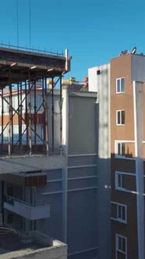 Vertical Video of Residential Construction With Workers Pouring Concrete and a Crane Moving Beams