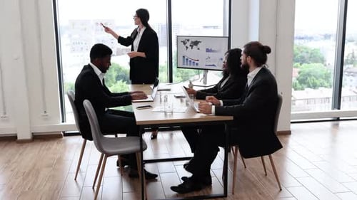 Business Woman Giving Presentation to Diverse Team in Modern Office
