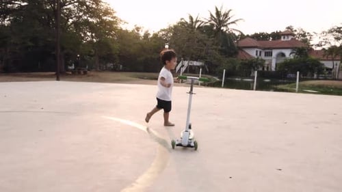 Happy Child Running Barefoot near Scooter at Sunset