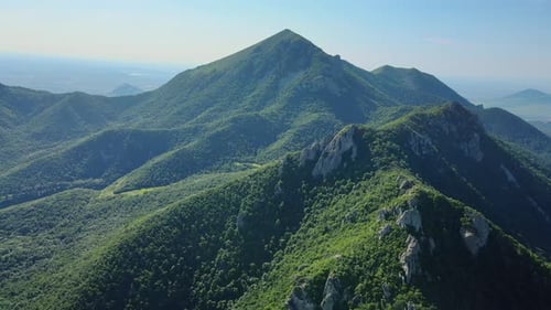 Aerial View of a Sunny Mountain with Treecovered Slopes