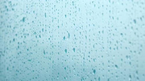 Rain Droplets on Glass Window on Blue Background