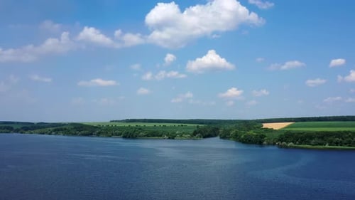 Tranquil atmosphere of summer nature. Flight over the beautiful blue river under the sky.