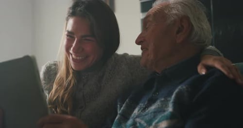 Cinematic shot of happy granddaughter and grandfather are having fun to make a selfie or video tec