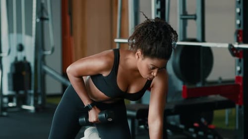 Woman With Dark Skin Exercising in Gym While Lifting Dumbbell