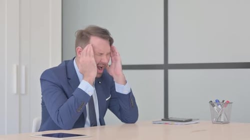 Stressed Businessman Suffering from Headache in Office
