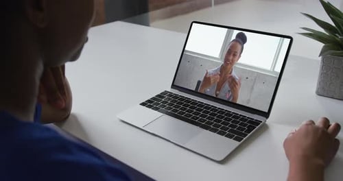African american woman talking on video call on laptop with female office colleague at home