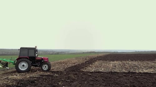 Red tractor plowing the field in Ukraine