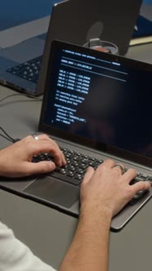Man Types Code on Laptop Computer in Office