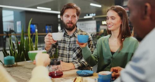 Multiethnic Young Adult Friends Communicating in the Cafeteria Sharing Table Enjoying Their Drinks