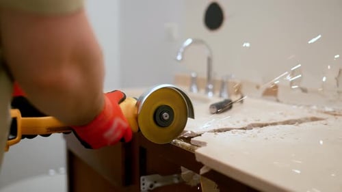 Construction Worker Using an Angle Grinder to Cut a Bathroom Countertop During Renovation Sparks