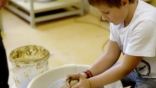Child Forms Clay on Pottery Wheel in Studio