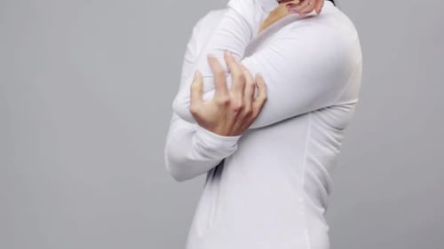 Man Holds and Massages Sore Elbow in Studio