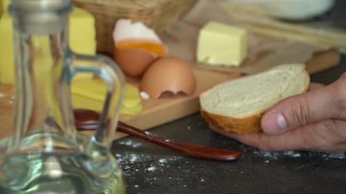 Close Up of Farmer Male Hands Spread Butter with Knife on Bread on Background of Rustic Products