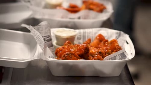 Hot Wings in To Go Container with Side of Sauce