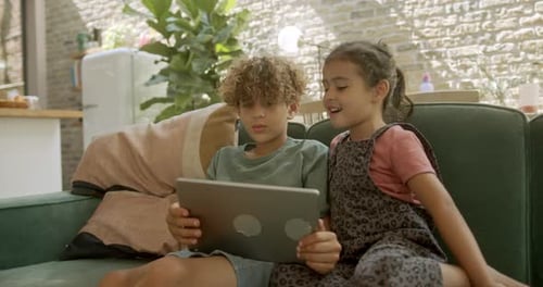 Kids on Couch Watching Tablet Together