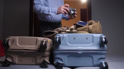 Man Inspects Camera Before Trip in Bedroom