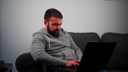 Man Using Laptop on Couch in Home Setting