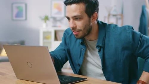 Excited man celebrates success while using laptop