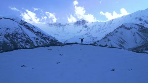 Aerial Circular View Male Hiker in Yellow Jacket on Hilltop Raising Hands Arms Up to the Sky Enjoy