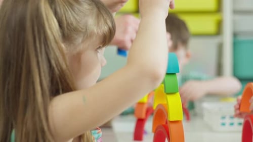 Girl Stacks Rainbow Blocks in Cheerful Classroom