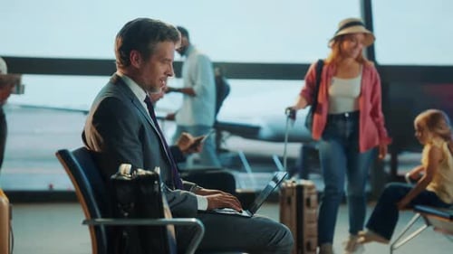 Un homme d'affaires s'est concentré sur son ordinateur portable dans un terminal d'aéroport en attendant son vol.