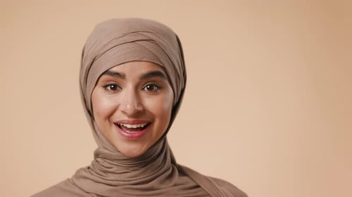 Junge Frau aus dem Nahen Osten lächelt und gestikuliert in einer Studioumgebung