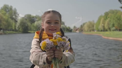Portrait of Happy Little Girl Holding Wildflowers by River