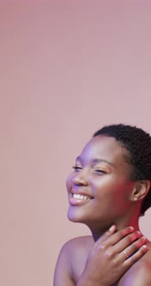 Vidéo verticale d'une heureuse femme afro-américaine aux cheveux noirs dans une lumière bleue et rose, au ralenti