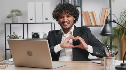 Young Adult Makes Heart With Hands at Desk