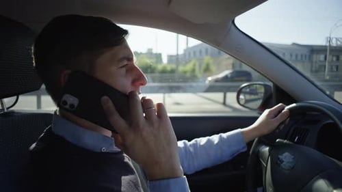 A Man is Talking on the Phone While Driving a Car