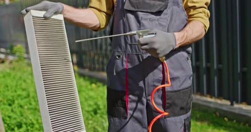 Trabajador limpiando un filtro de aire obstruido con aire comprimido