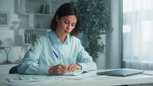 Woman Taking Notes in Home Office Environment