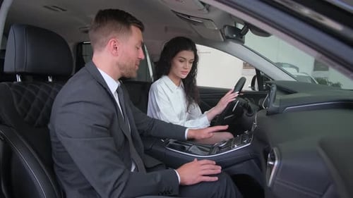 Concentrated Young Female Customer Sits Behind the Wheel of a New Car Takes a Test Drive