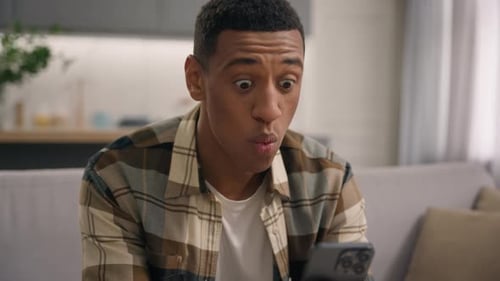 Man Reacts to Content on Smartphone in Home