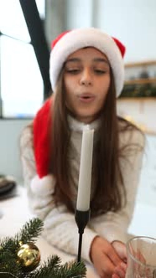 Friendly Woman Wearing a Festive Red Santa Hat Blowing a Candle
