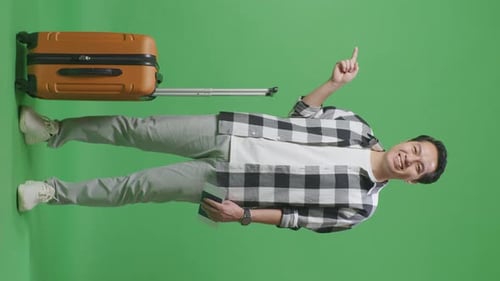 Male Traveler With Luggage And Passport Smiling And Pointing To Side In The Green Screen