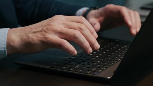 Hände eines unbekannten Managers, der auf dem Laptop am Schreibtisch tippt