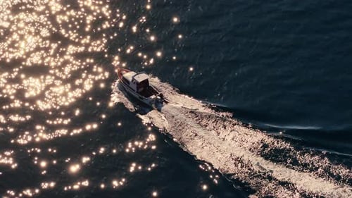 Aerial drone view of a small motorboat speeding across the water, leaving a white foamy trail behind