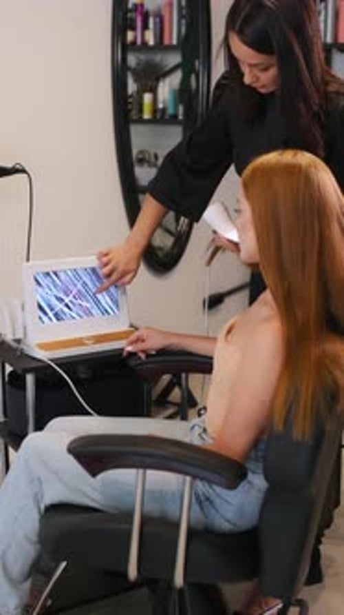 Macro view, examining the hair. Woman is in a beauty salon with hair stylist.