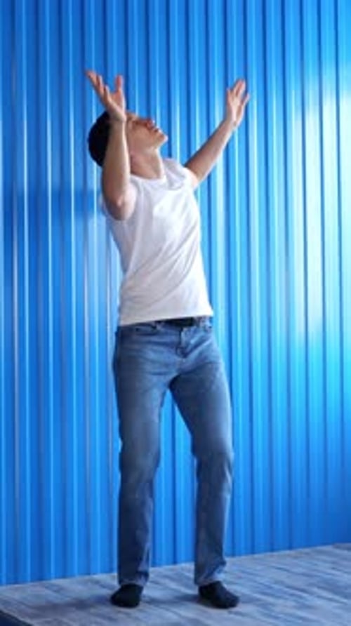 Young Adult Man Dancing in Front of Blue Background