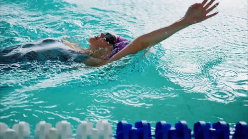 Woman Swimming Backstroke in Indoor Swimming Pool