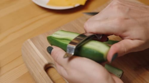 A Woman Slices Fresh Cucumber into Thin Strips with a Special Vegetable Knife, in Slow Motion.